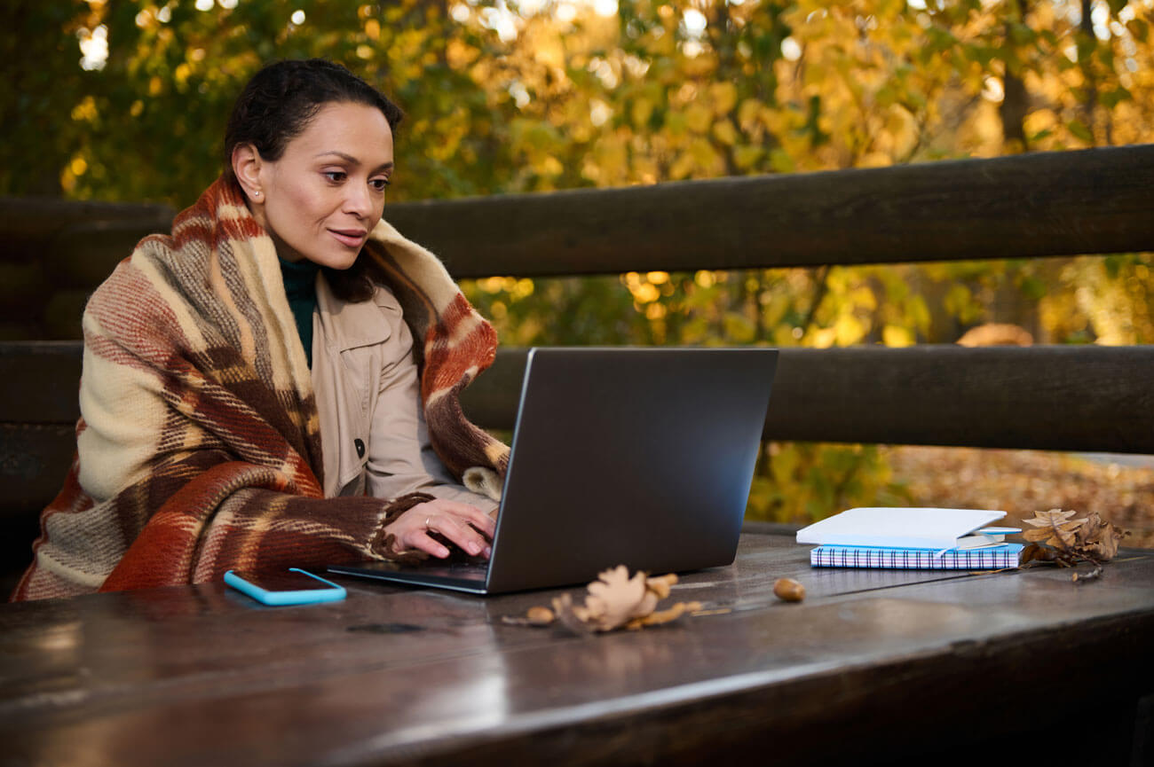 Symbolbild - Workation: Frau arbeitet in einem Park an einem Laptop