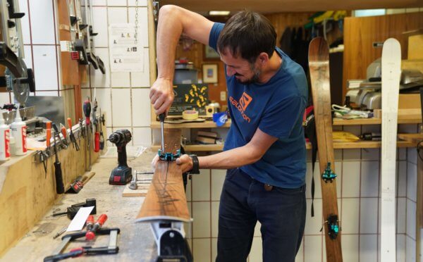 Peter Pfeifer in der SPURart Werkstatt, wie er gerade die Bindungen auf ein individualisiertes Paar Ski montiert.