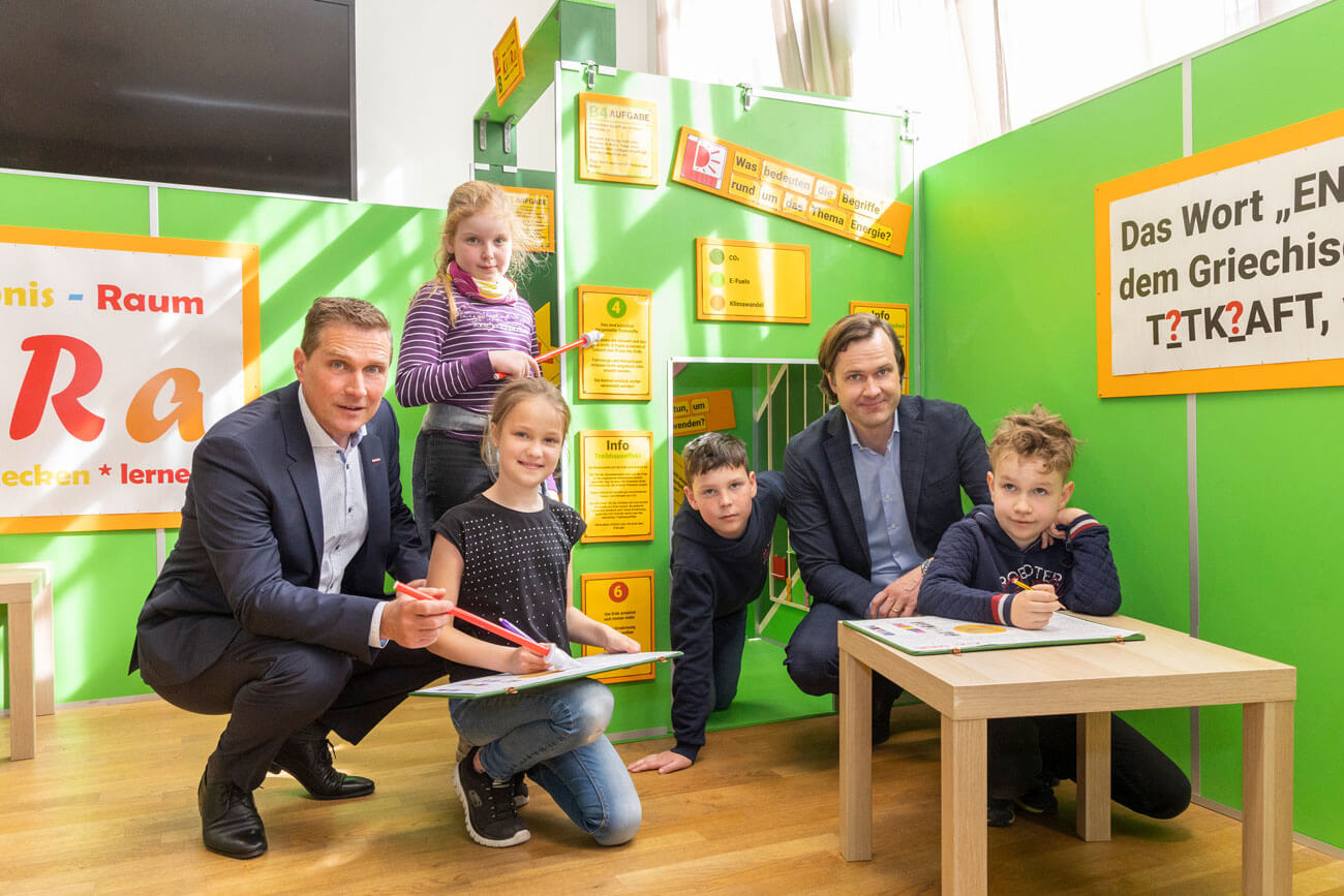 Franz Jirka (Bezirksobmann Innsbruck-Stadt, l.) und Alexander Gutmann (Fachgruppenobmann Energiehandel, r.) gemeinsam mit Kindern der VS Flaurling beim Kinder-Erlebnis-Raum ENERGIE (KieRa).
